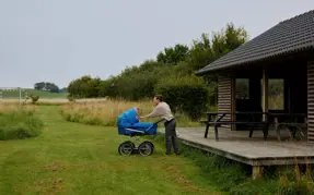 Mor med barnevogn ved boldbanen